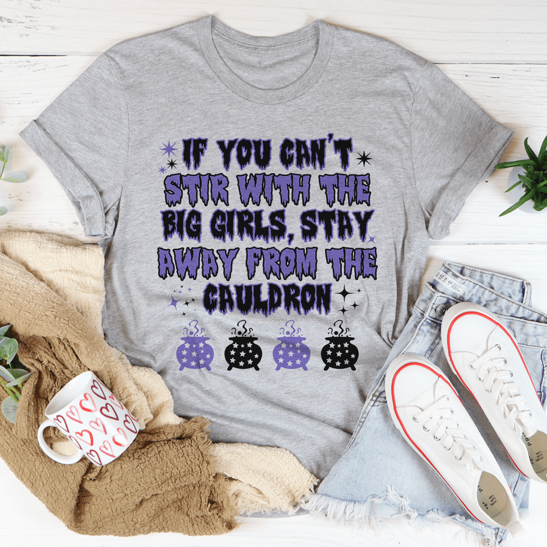 A stylish black t-shirt featuring the phrase 'If You Can't Stir With The Big Girls Stay Away From The Cauldron' in bold white lettering.
