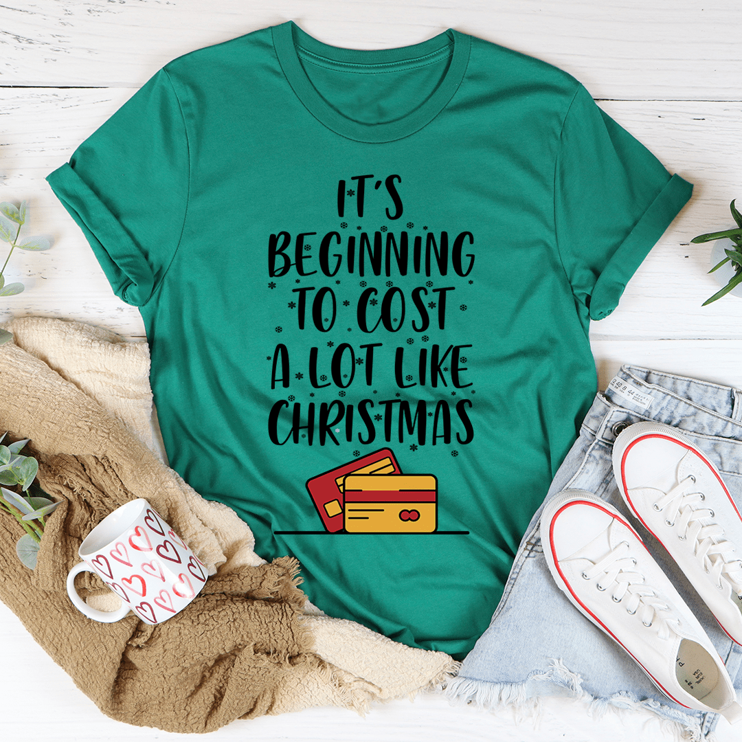 A festive t-shirt featuring the phrase 'It's Beginning To Cost A Lot Like Christmas' printed in vibrant colors on a soft cotton fabric.