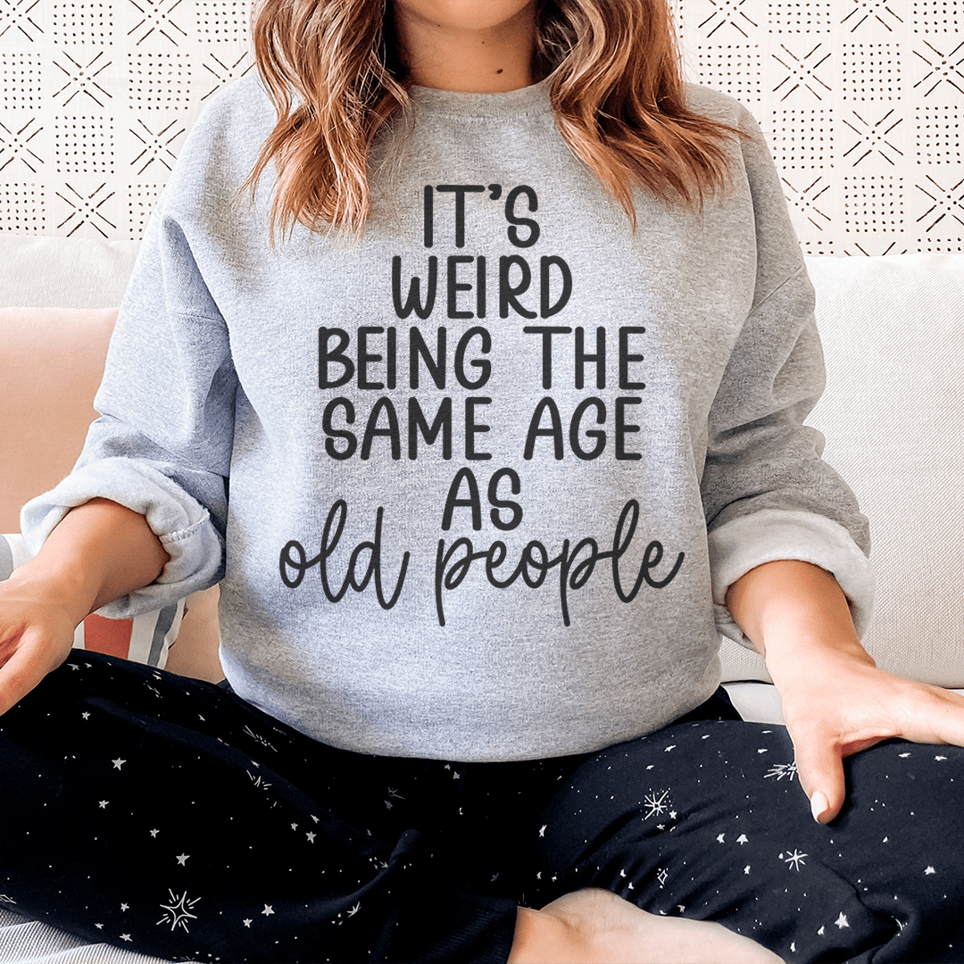 Cozy sweats featuring the phrase 'It's Weird Being The Same Age As Old People', designed by top artists, showcasing a stylish and comfortable fit.