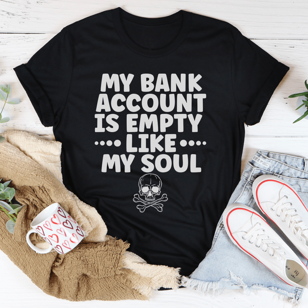 A black t-shirt featuring the phrase 'My Bank Account Is Empty Like My Soul' in bold white lettering, showcasing its soft fabric and durable stitching.