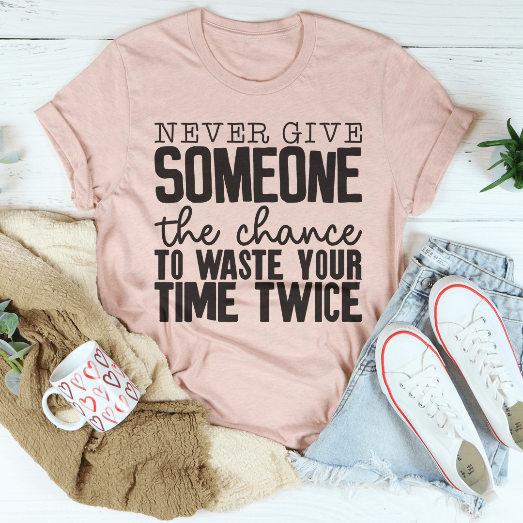 A stylish black t-shirt featuring the phrase 'Never Give Someone The Chance To Waste Your Time Twice' printed in bold letters.