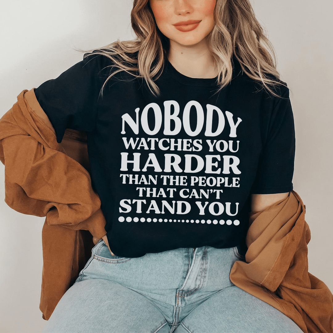 A stylish t-shirt featuring the phrase 'Nobody Watches You Harder Than The People That Can't Stand You', made from soft cotton with double stitching.