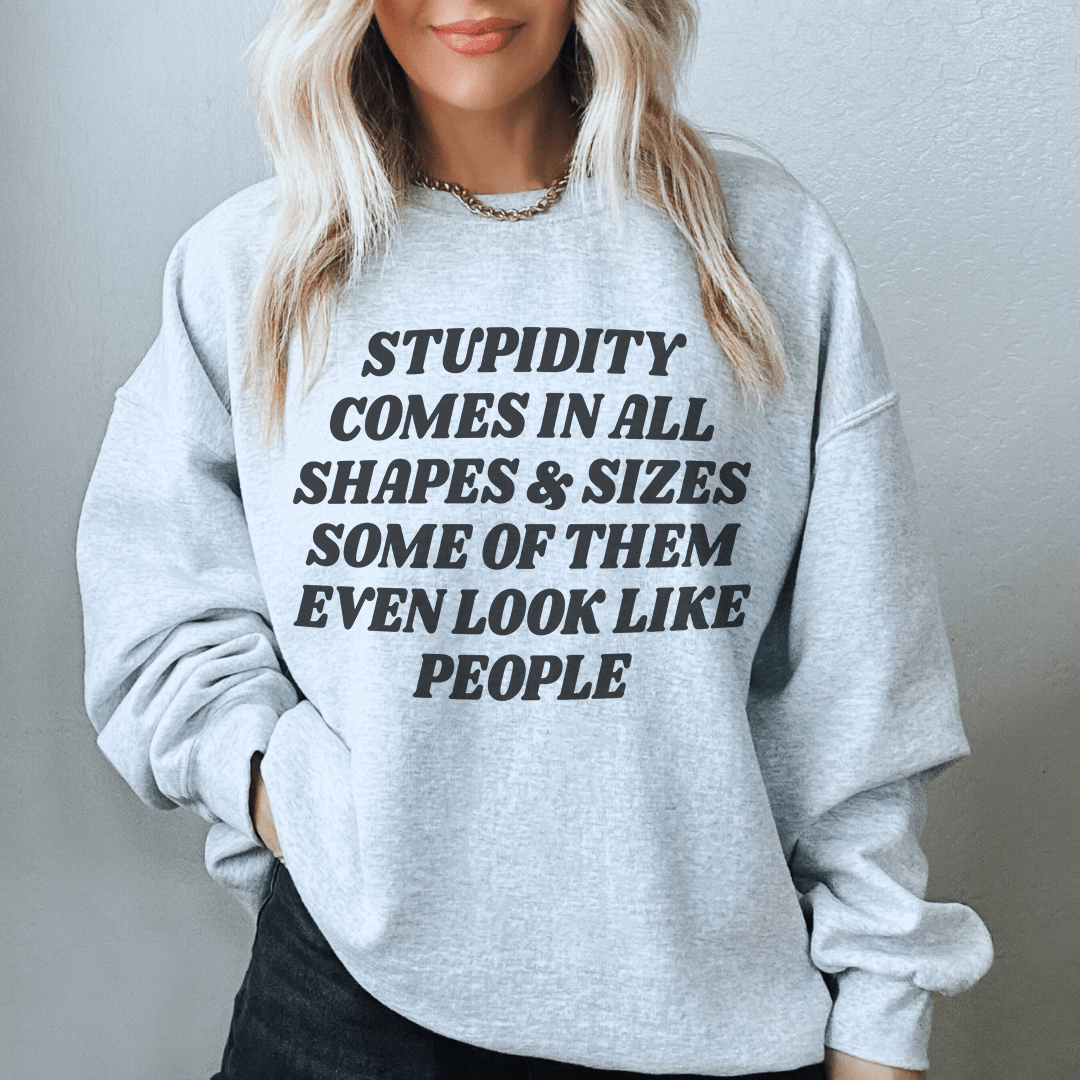 A cozy sweatshirt featuring the phrase 'Stupidity Comes In All Shapes and Sizes', designed by top artists, showcasing vibrant colors and a comfortable fit.