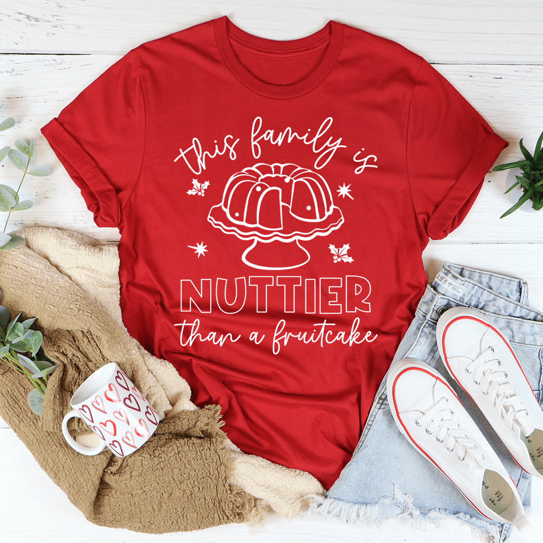 A humorous t-shirt featuring the phrase 'This Family Is Nuttier Than A Fruitcake' printed on soft ring-spun cotton fabric.