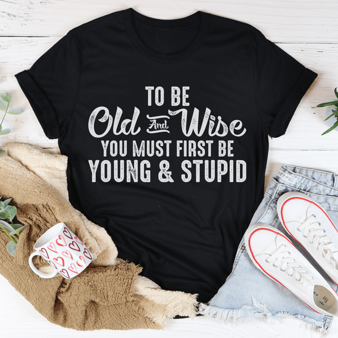 To Be Old & Wise Tee in various colors, showcasing its soft cotton fabric and double stitching details.
