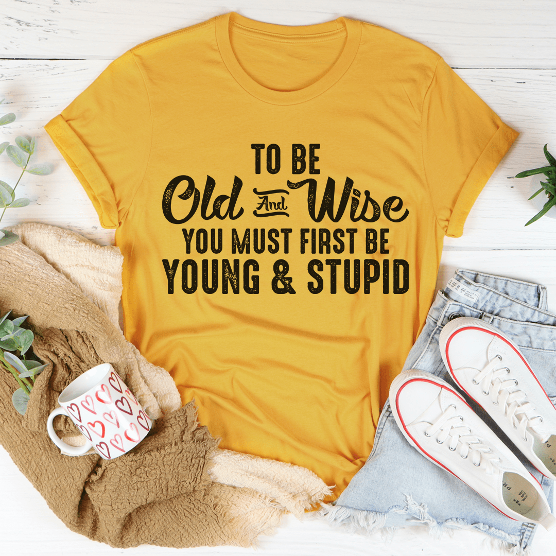 To Be Old & Wise Tee in various colors, showcasing its soft cotton fabric and double stitching details.