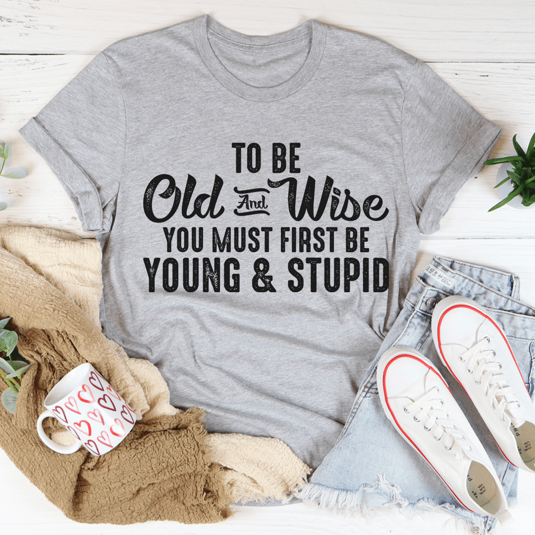 To Be Old & Wise Tee in various colors, showcasing its soft cotton fabric and double stitching details.