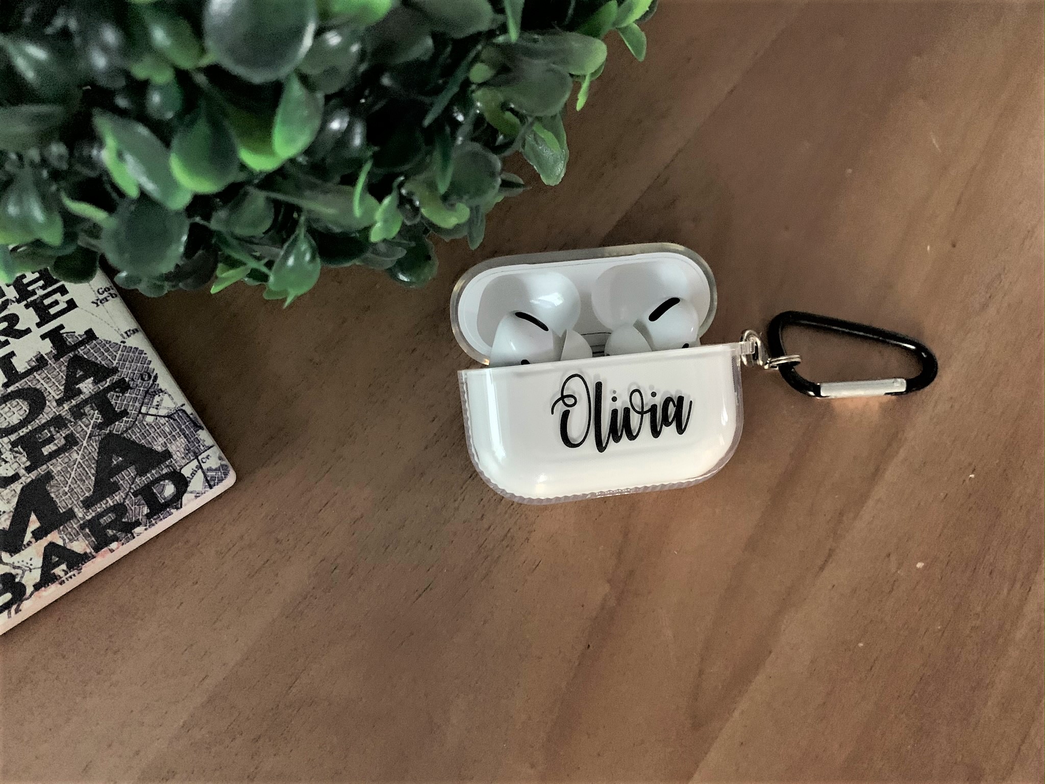 A personalized transparent case for Apple AirPods Pro, showcasing a sleek design with a metal strap attached.