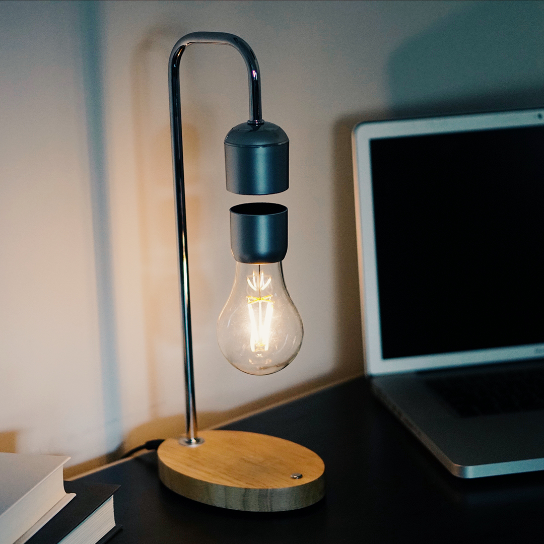 A modern levitating wireless light bulb lamp with a wooden oak finish base and a floating light bulb, showcasing innovative design and technology.