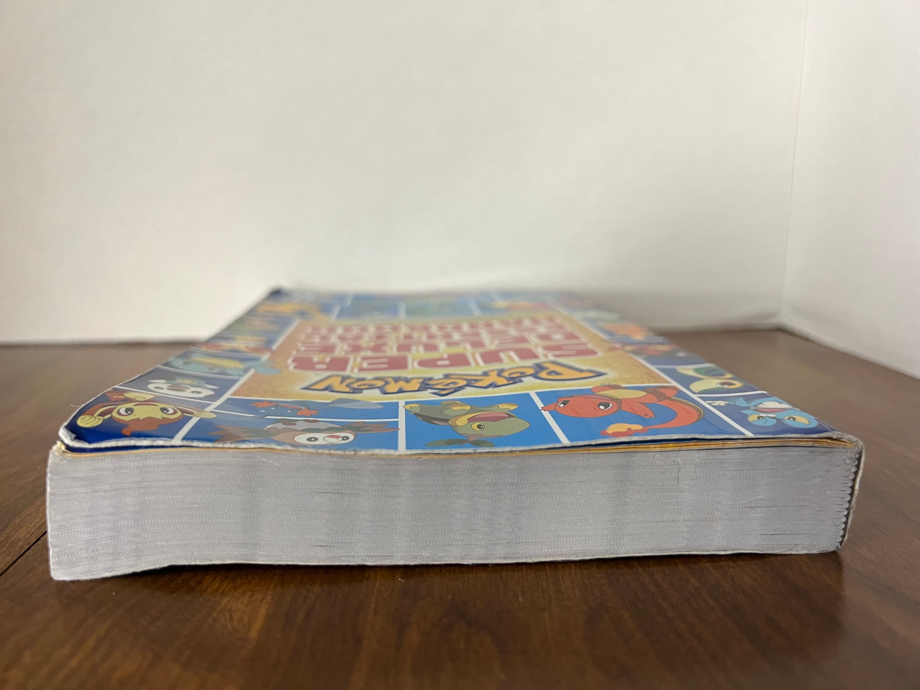 Cover of the Pokémon Super Deluxe Essential Handbook featuring colorful illustrations of various Pokémon characters.