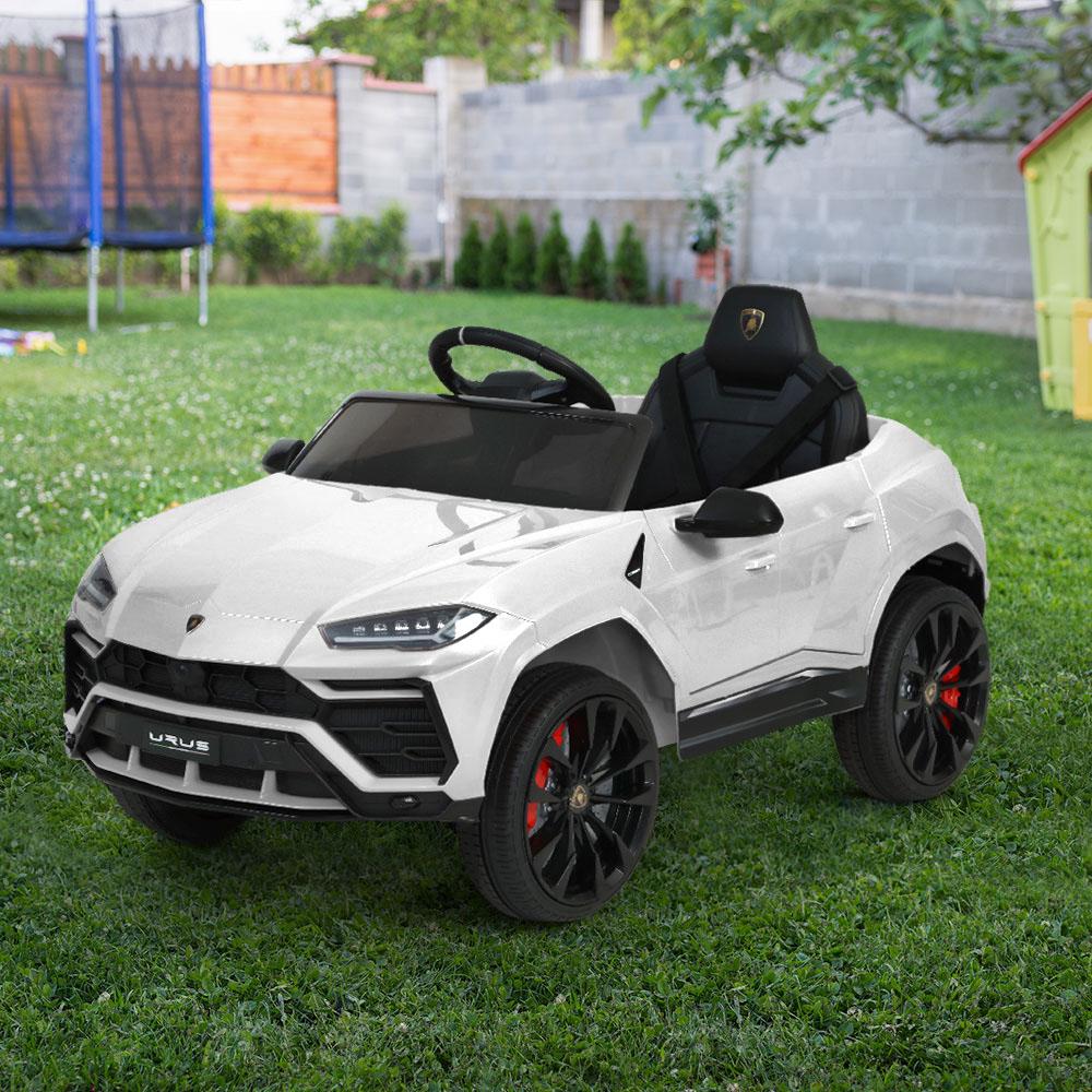 A white 12V Electric Kids Ride On Toy Car designed as a licensed Lamborghini URUS, featuring stylish working doors, headlights, and a digital dashboard.