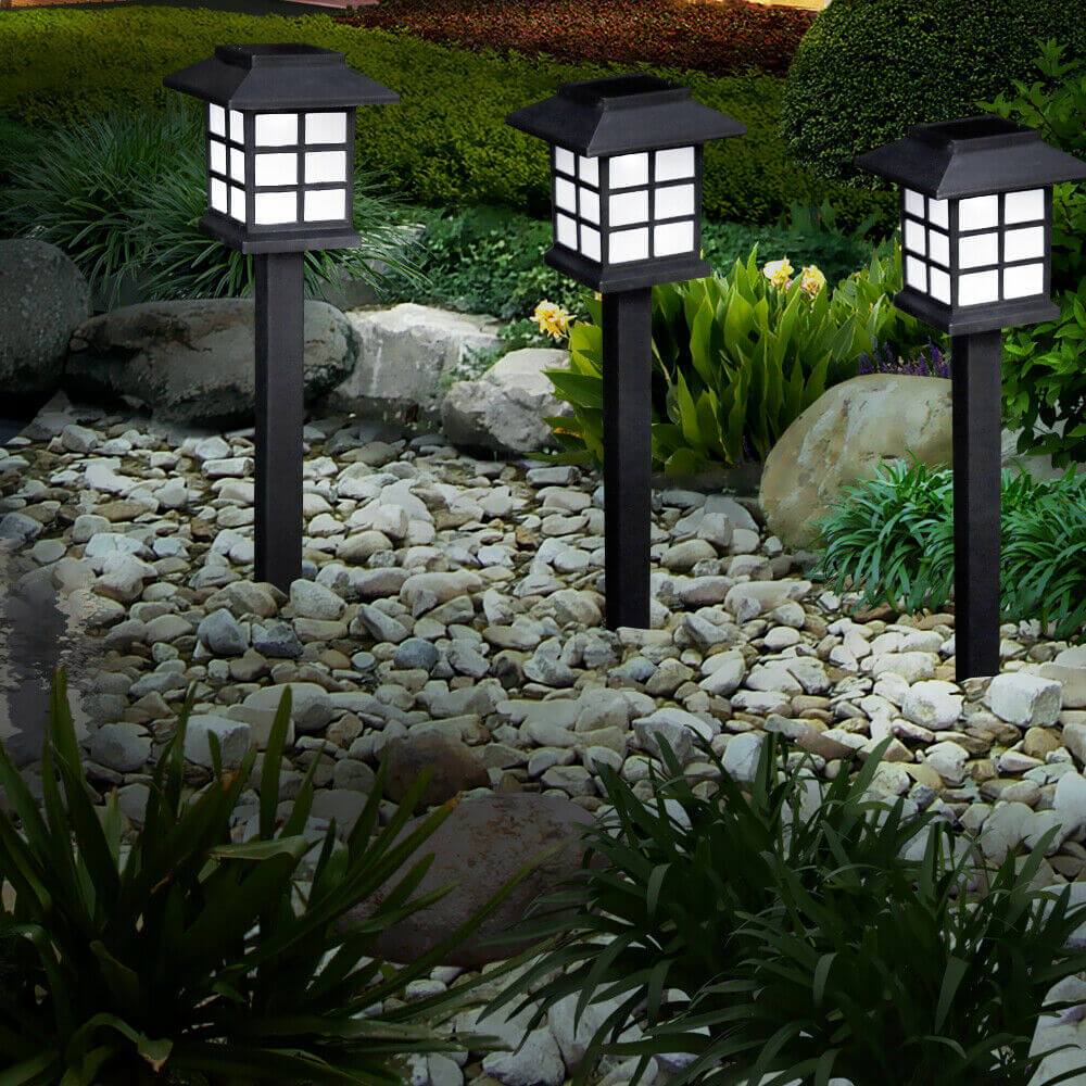 A set of 12 LED solar-powered garden lights illuminating a pathway, showcasing their sleek design and bright white light.