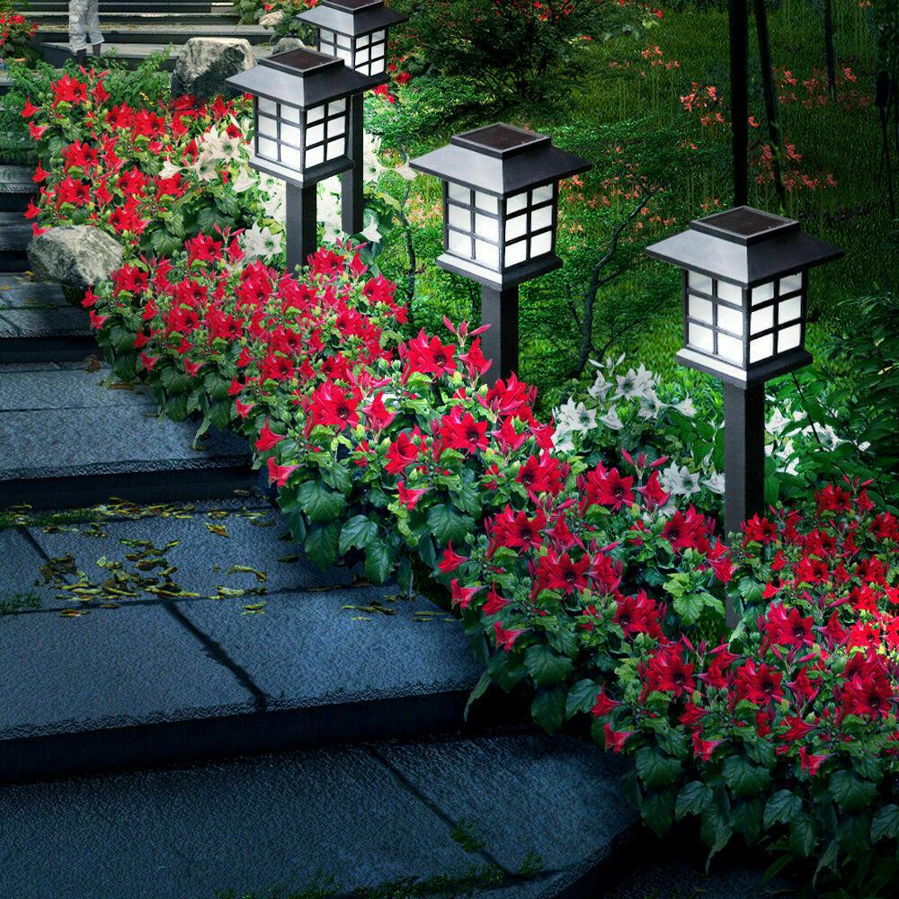 A set of 12 LED solar-powered garden lights illuminating a pathway, showcasing their sleek design and bright white light.