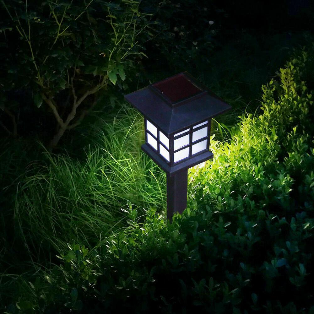 A set of 12 LED solar-powered garden lights illuminating a pathway, showcasing their sleek design and bright white light.