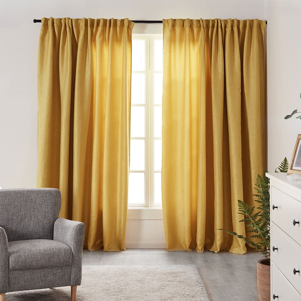 Elegant mustard blockout curtains hanging in a living room, showcasing their rich texture and vibrant color.