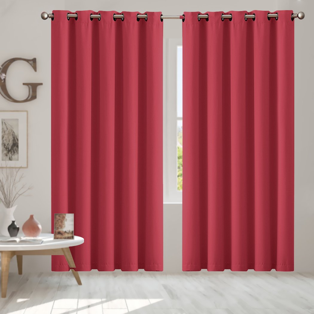Two elegant blockout curtain panels in vibrant color, featuring eyelet design and triple weave fabric, hanging in a stylish room.