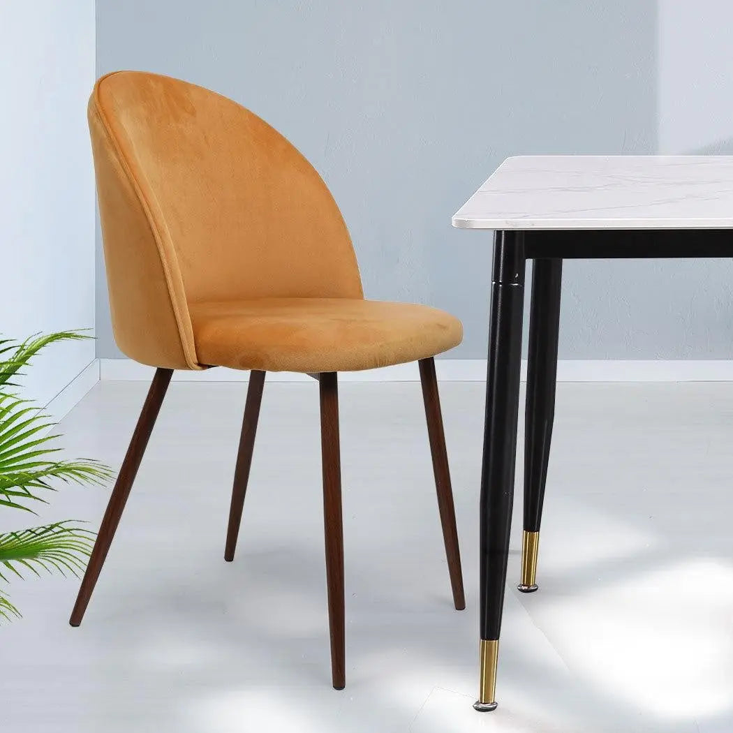 Set of two mustard dining chairs with plush velvet upholstery and sturdy steel legs, perfect for kitchen or lounge use.