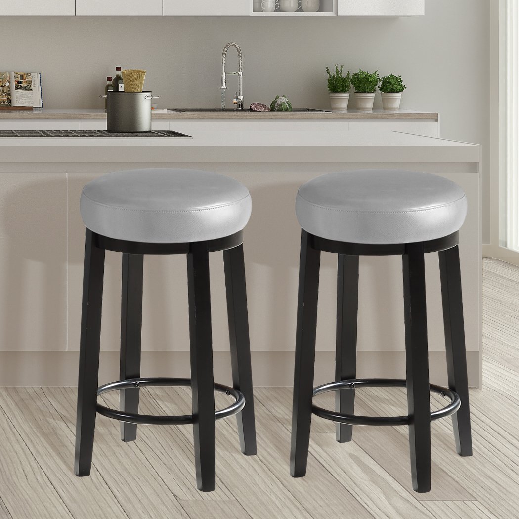Two Levede 75cm swivel bar stools in dove grey with solid wood frame and PU leather upholstery, featuring a bronze-finished footrest.
