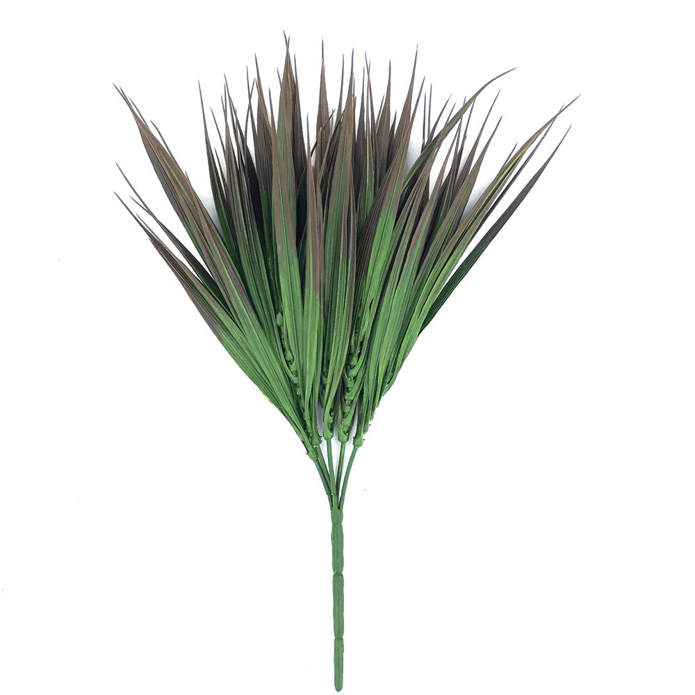 A 35cm tall artificial grass plant with brown tips, showcasing realistic foliage in mixed shades of green, perfect for indoor and outdoor decoration.