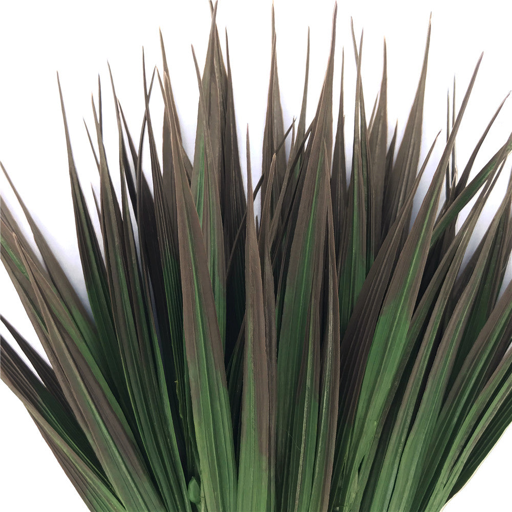 A 35cm tall artificial grass plant with brown tips, showcasing realistic foliage in mixed shades of green, perfect for indoor and outdoor decoration.