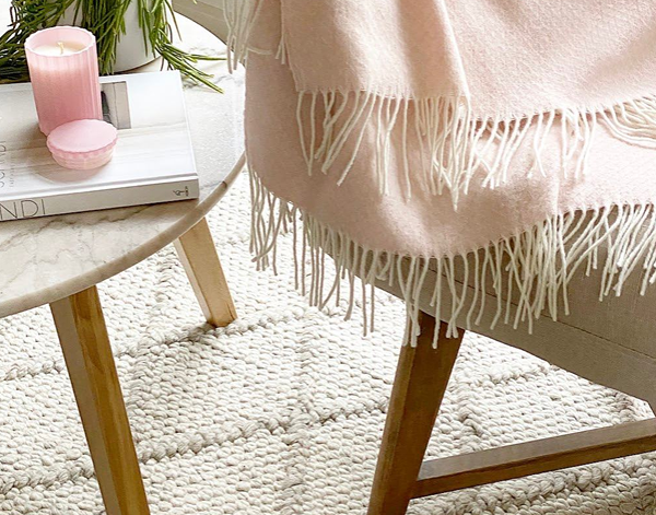 Chiswick Throw blanket in blush color, made from luxurious merino wool and cashmere blend, elegantly draped on a cozy sofa.
