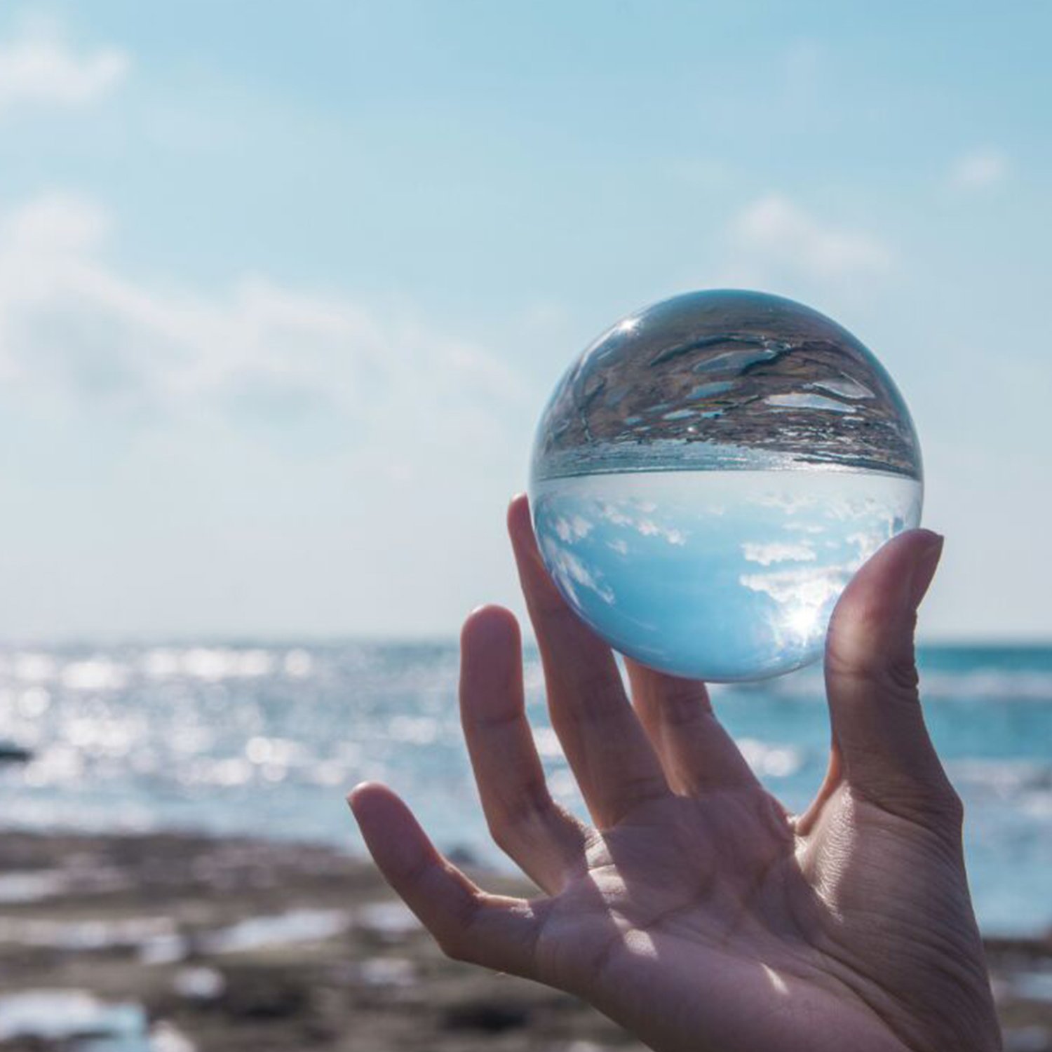 Clear Glass Healing Crystal Ball Sphere on a reflective surface, showcasing its transparent design and perfect for photography props.