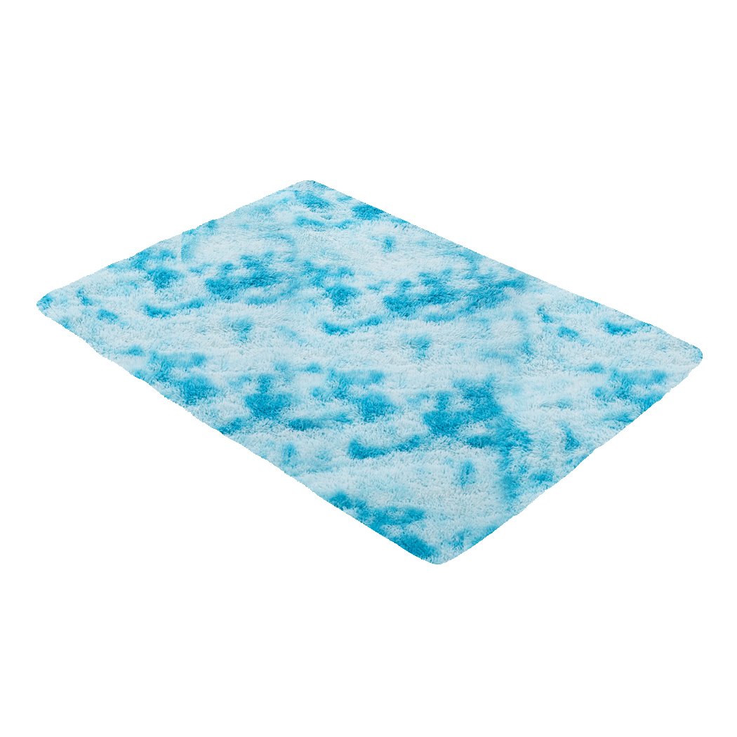 A large, soft shaggy floor rug with a vibrant tie-dyed pattern, showcasing its plush texture and non-slip silicone bottom.