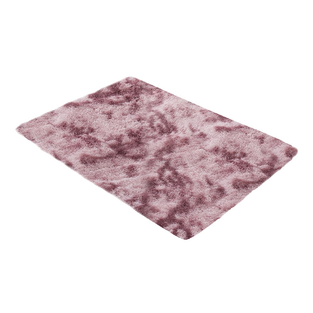 A large, soft shaggy floor rug with a vibrant tie-dyed pattern, showcasing its plush texture and non-slip silicone bottom.