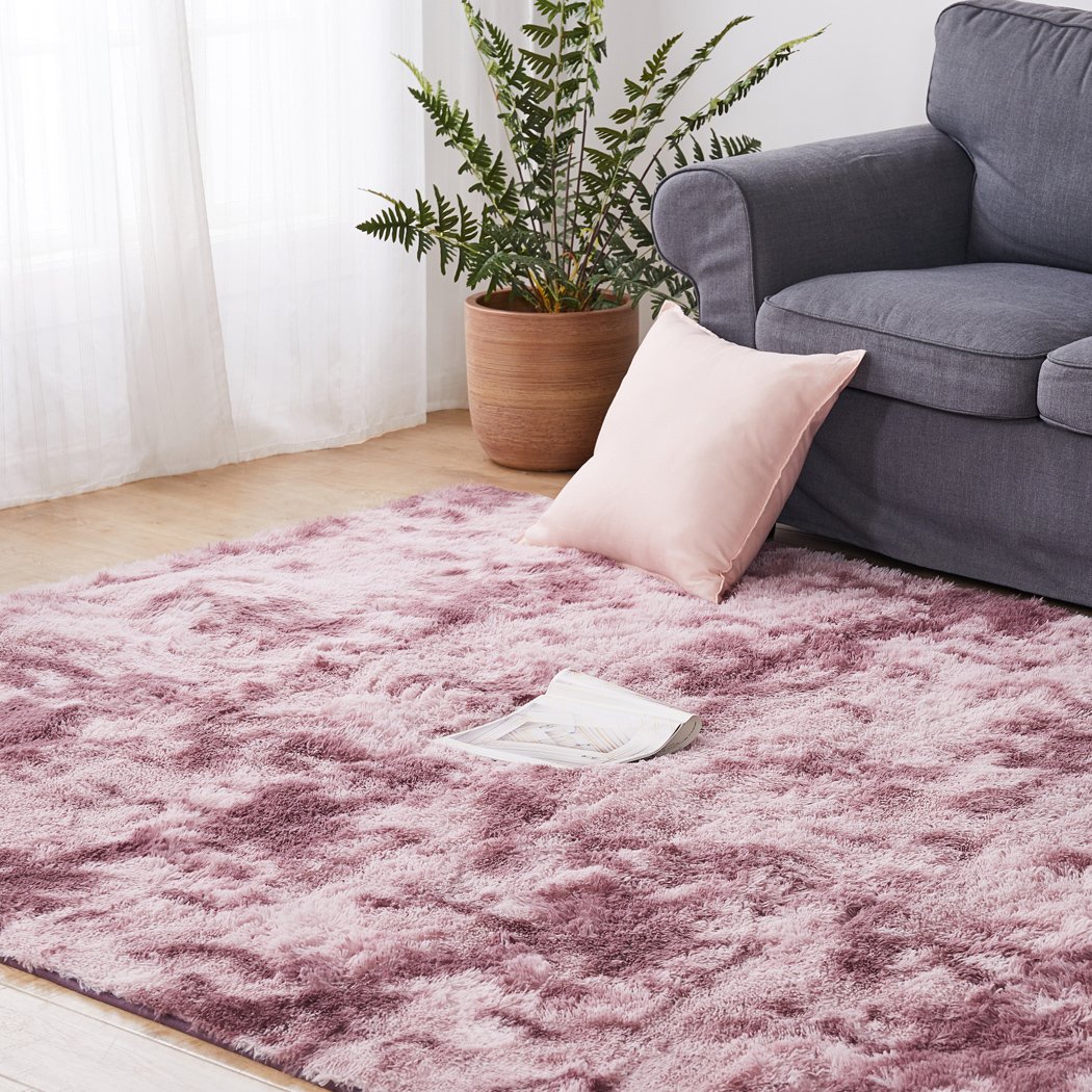 A large, soft shaggy floor rug with a vibrant tie-dyed pattern, showcasing its plush texture and non-slip silicone bottom.