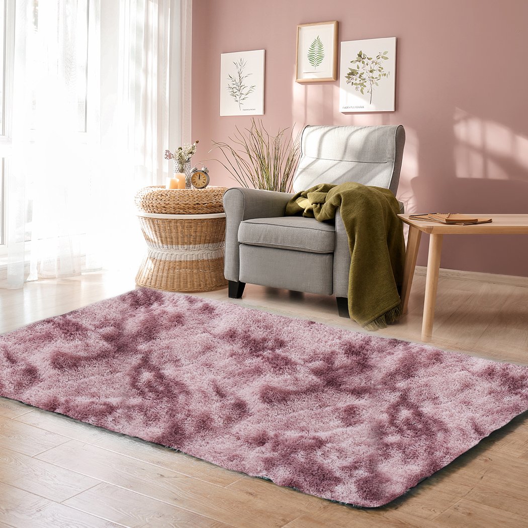 A large, soft shaggy floor rug with a vibrant tie-dyed pattern, showcasing its plush texture and non-slip silicone bottom.