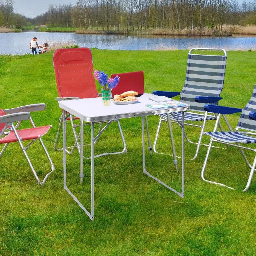 A lightweight and portable folding camping table made of aluminum, set up outdoors with a scenic background, perfect for picnics and camping.