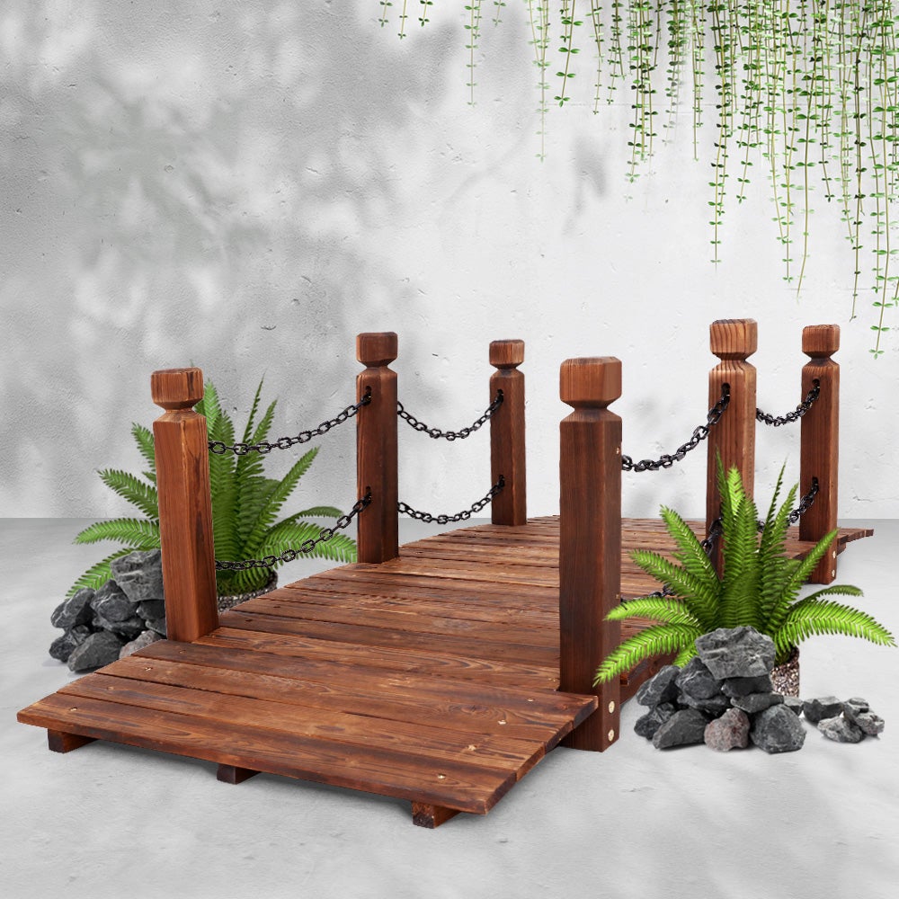 A rustic wooden garden bridge made of burnt fir wood, featuring an arch design and rustic chains along the railings, set in a lush garden landscape.