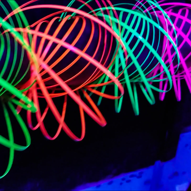 Kinetic Glow Koil 2-Pack featuring vibrant pink/orange and yellow/green colors, glowing under UV light.