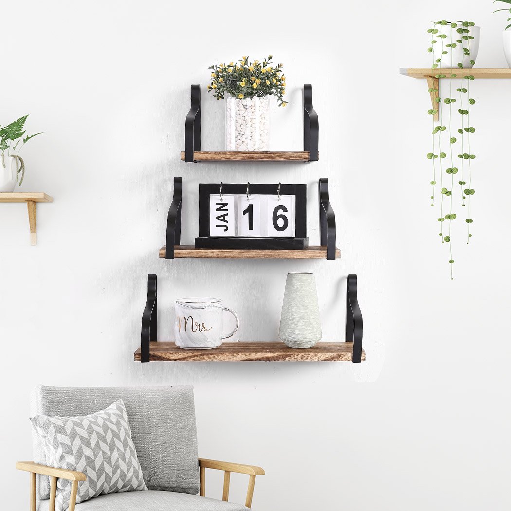 Levede Floating Shelf Brackets showcasing three wooden shelves mounted on a wall, displaying decorative items and plants.