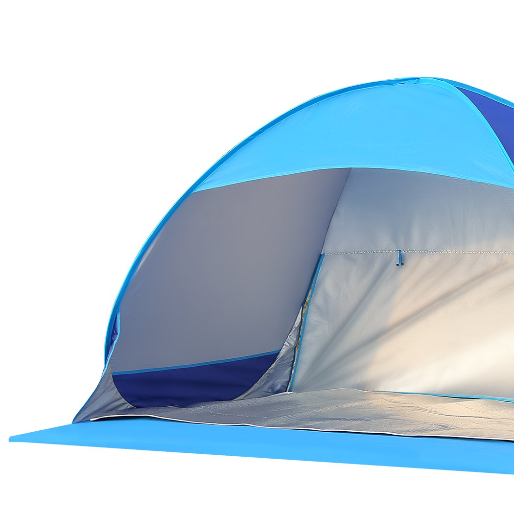 Mountview Pop Up Tent set up on a beach, spacious enough for 2-3 people, featuring a blue color and surrounded by sand and beach scenery.