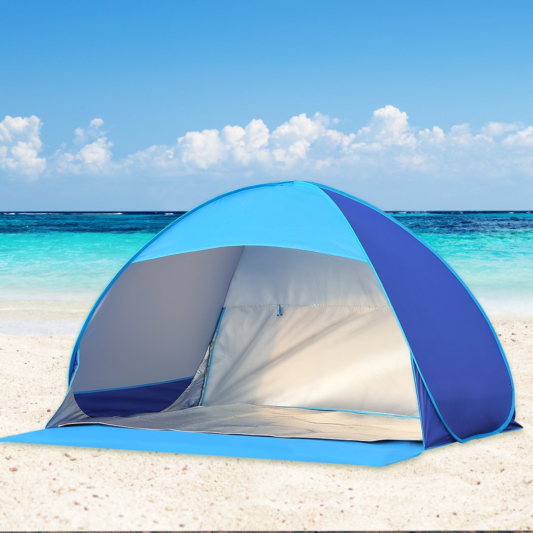 Mountview Pop Up Tent set up on a beach, spacious enough for 2-3 people, featuring a blue color and surrounded by sand and beach scenery.