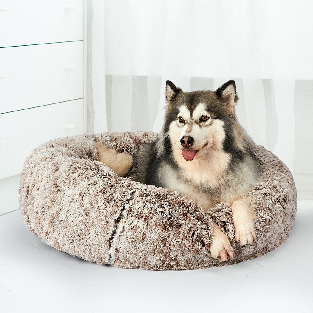 A cozy coffee-colored donut-shaped pet bed with plush material and raised rim, perfect for dogs and cats to relax and feel secure.