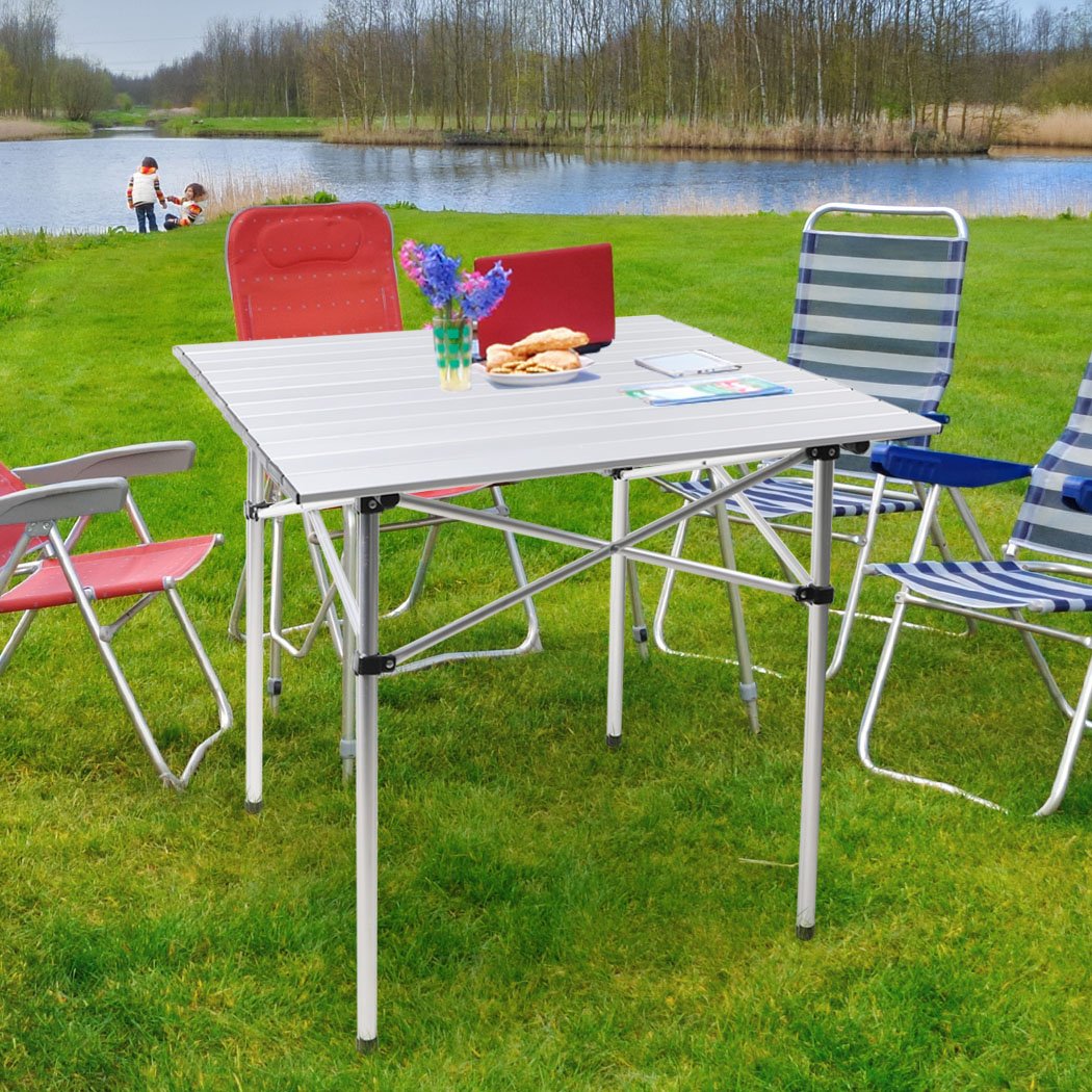 A lightweight and portable Roll Up Camping Table made of aluminium, set up outdoors with food and drinks on it, showcasing its sturdy design and anti-slip feet.