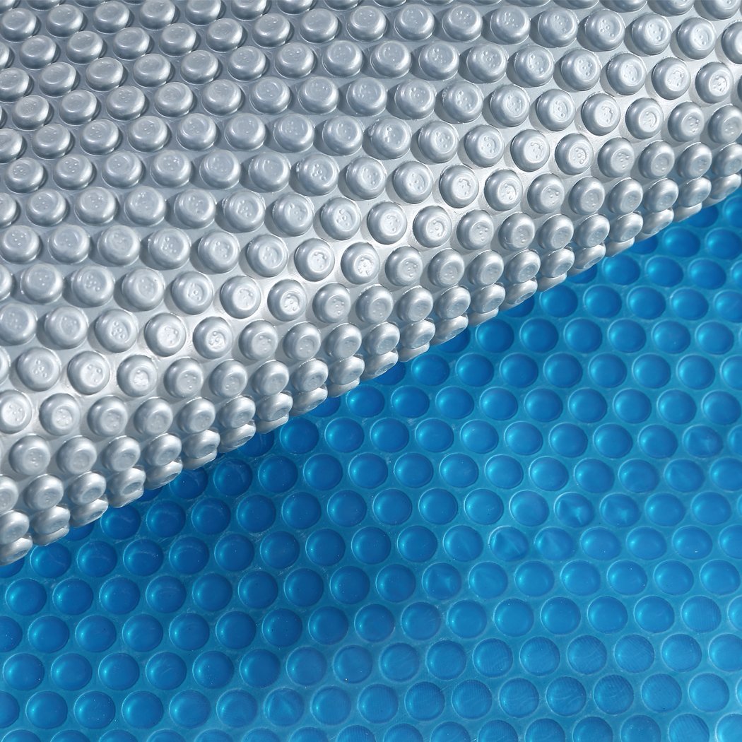 Solar Swimming Pool Cover with blue top and silver bottom, designed to keep pools warm and clean, featuring durable bubbles.