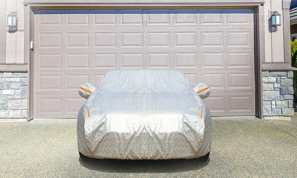 Waterproof adjustable large car cover protecting a vehicle from rain and sun, featuring reflective strips and zippers.