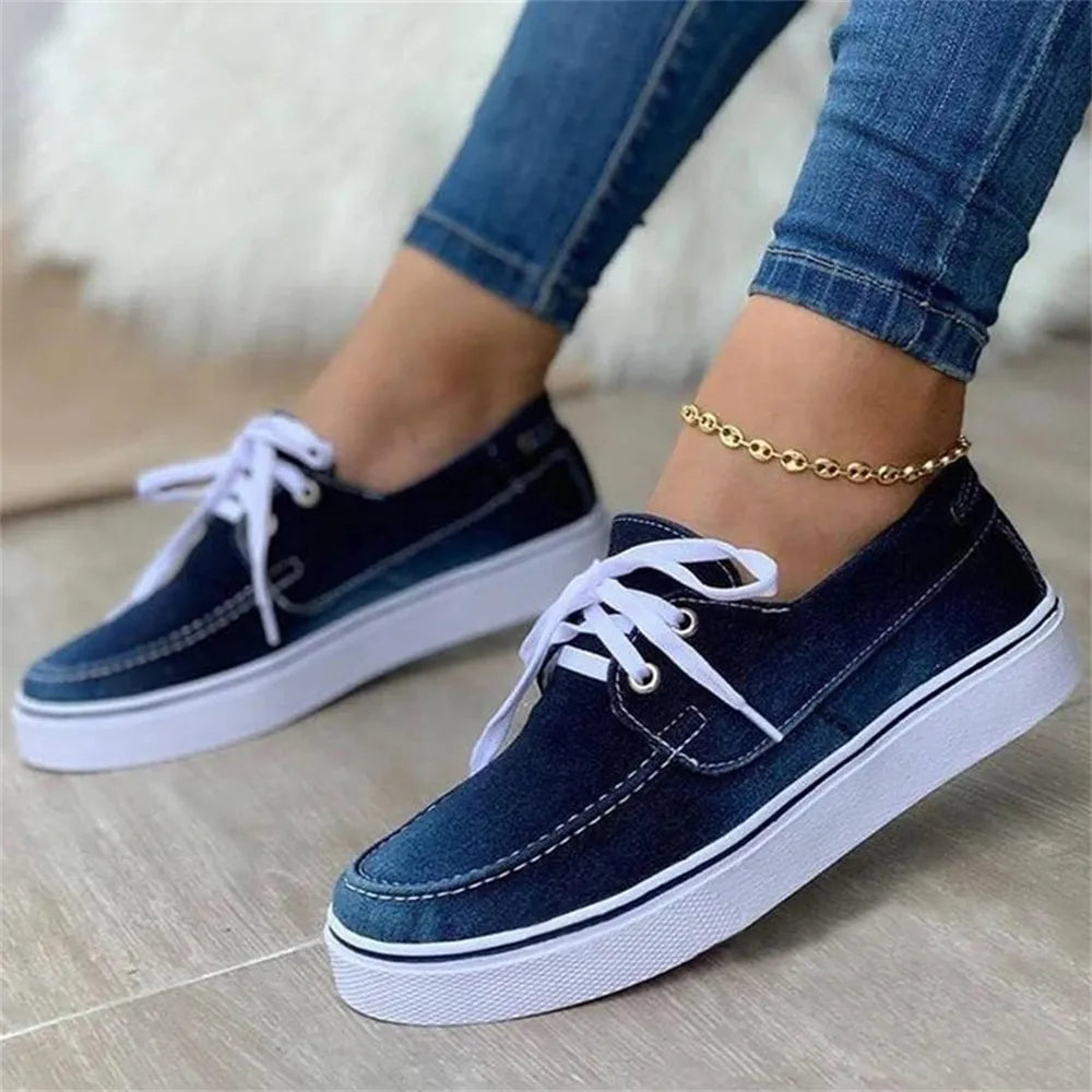 A pair of women's canvas shoes in solid denim fabric with a lace-up design, perfect for casual spring wear.