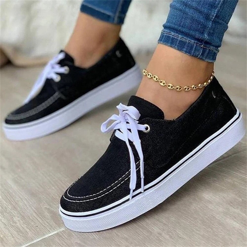 A pair of women's canvas shoes in solid denim fabric with a lace-up design, perfect for casual spring wear.