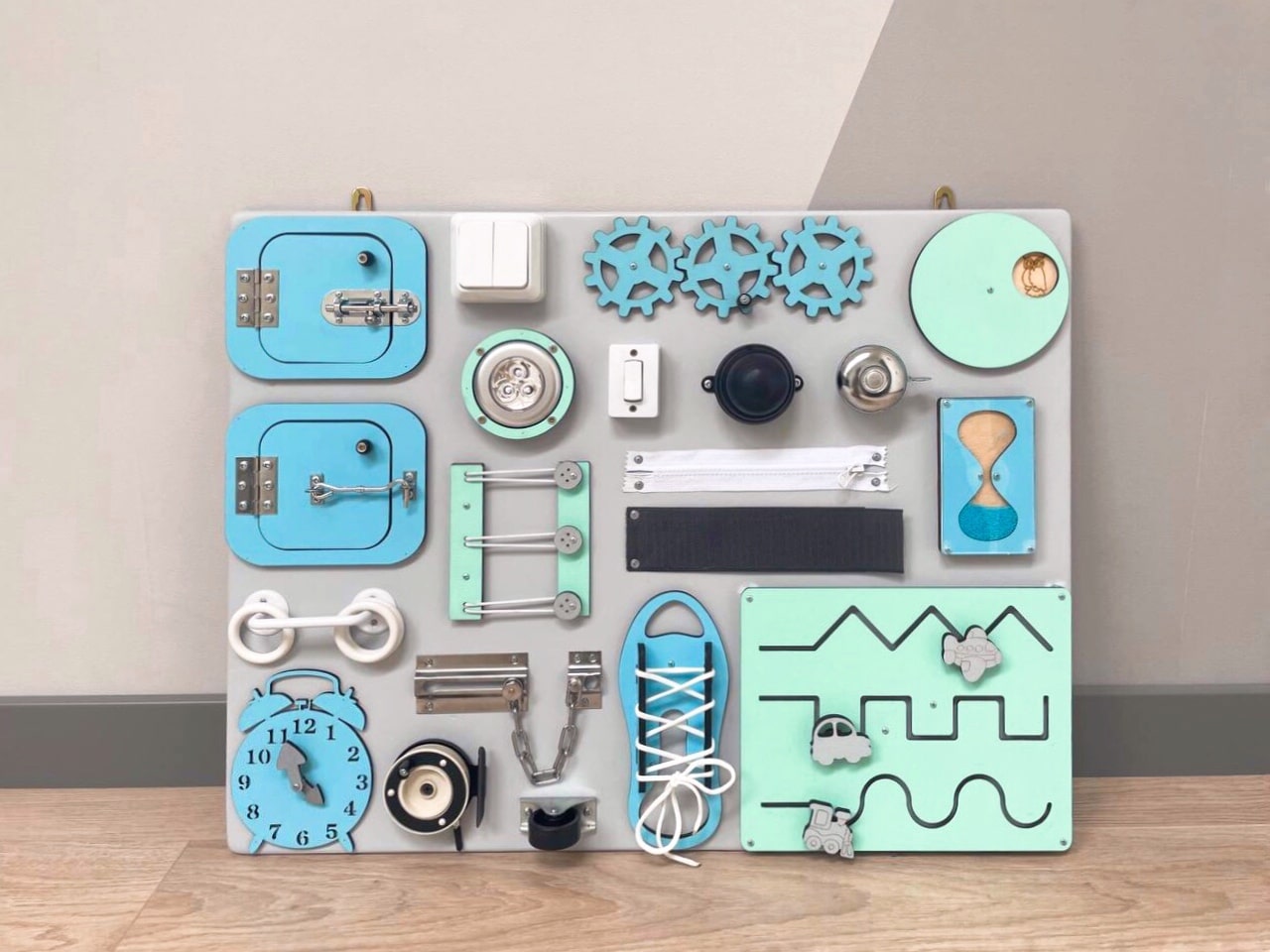 Busy Board MAXI in blue-mint color featuring various engaging activities for toddlers, designed to enhance motor skills and creativity.