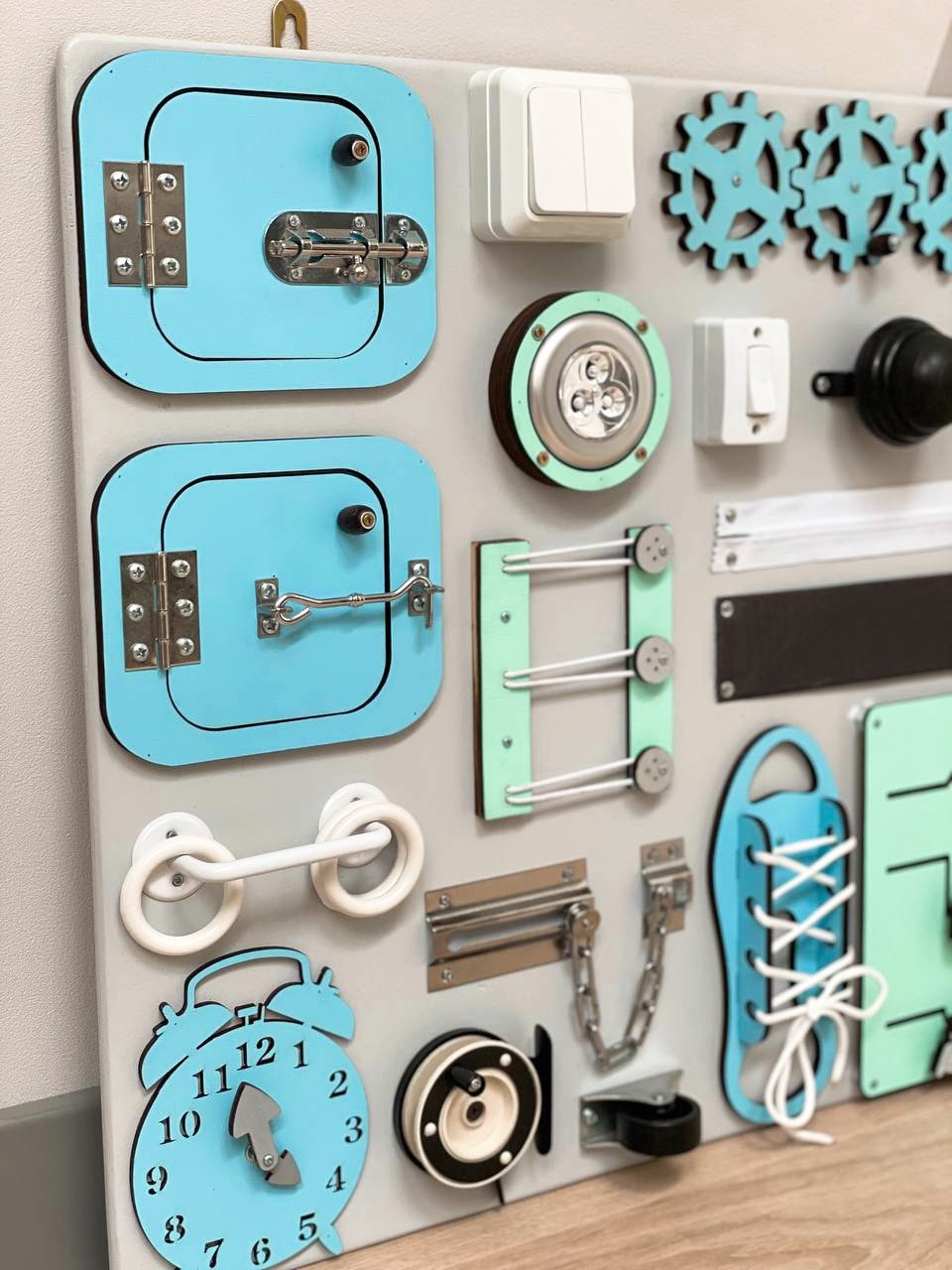 Busy Board MAXI in blue-mint color featuring various engaging activities for toddlers, designed to enhance motor skills and creativity.