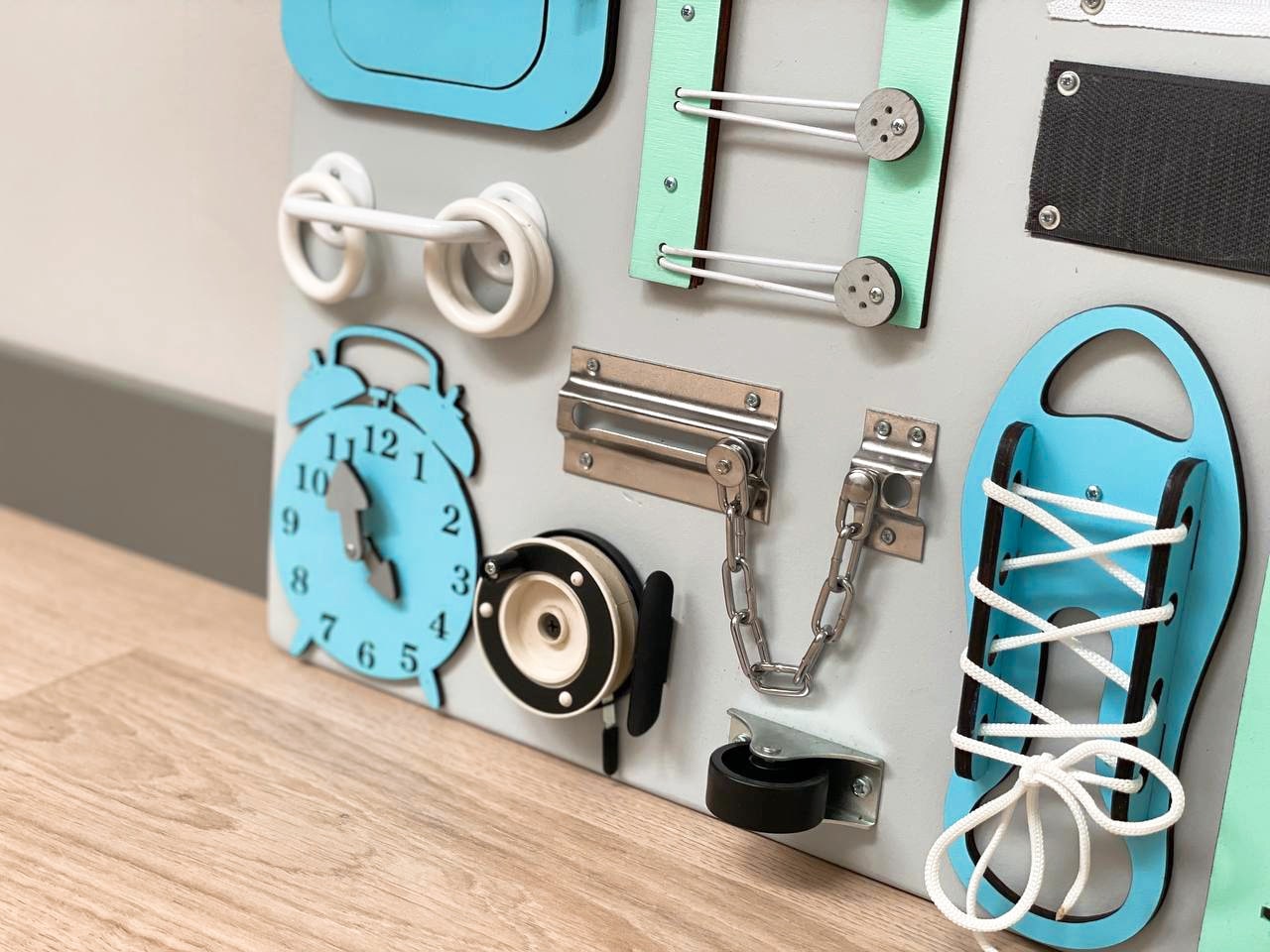 Busy Board MAXI in blue-mint color featuring various engaging activities for toddlers, designed to enhance motor skills and creativity.