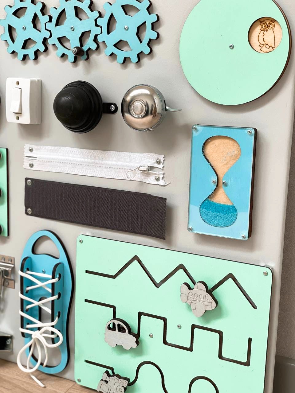 Busy Board MAXI in blue-mint color featuring various engaging activities for toddlers, designed to enhance motor skills and creativity.