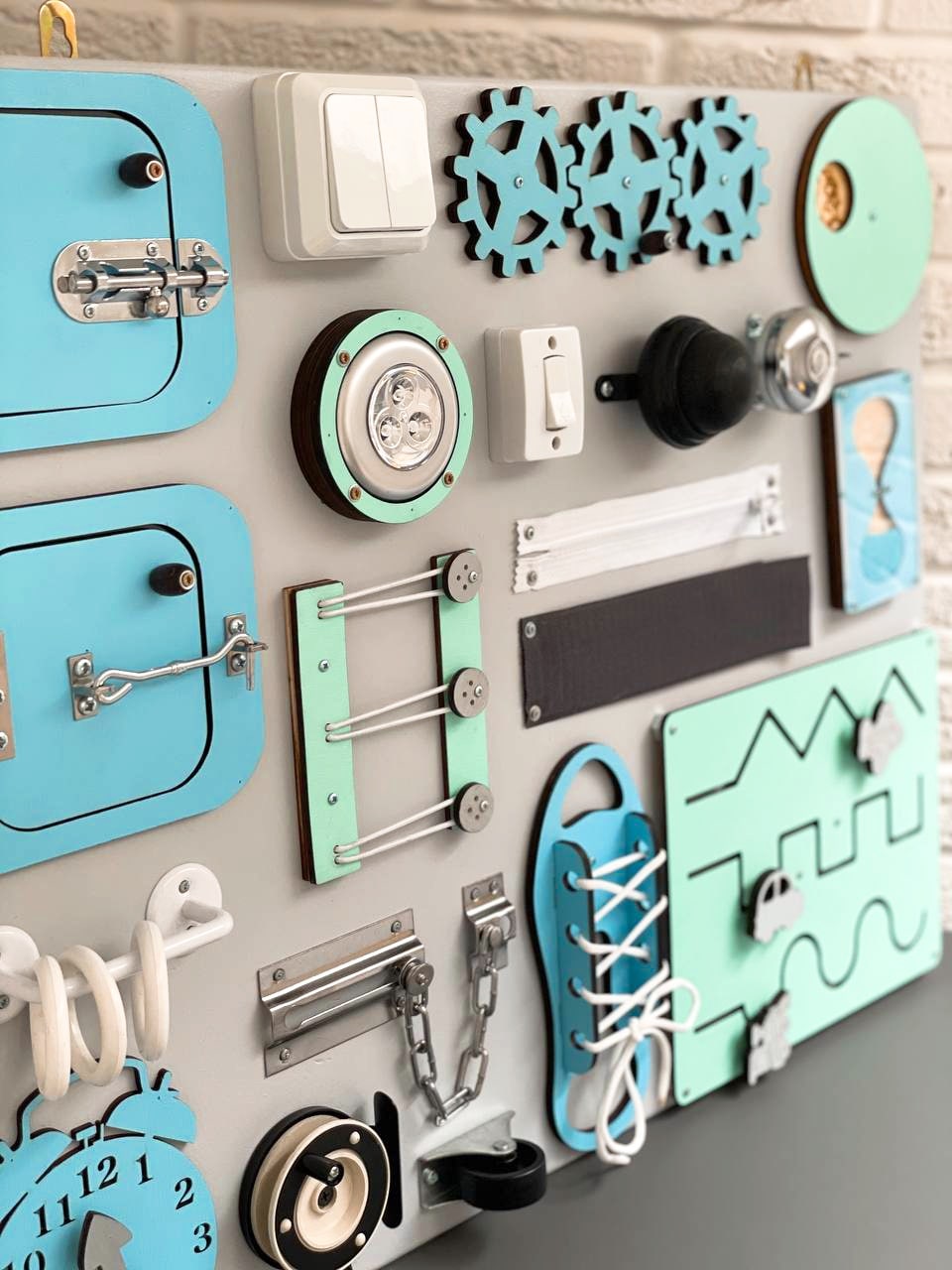 Busy Board MAXI in blue-mint color featuring various engaging activities for toddlers, designed to enhance motor skills and creativity.