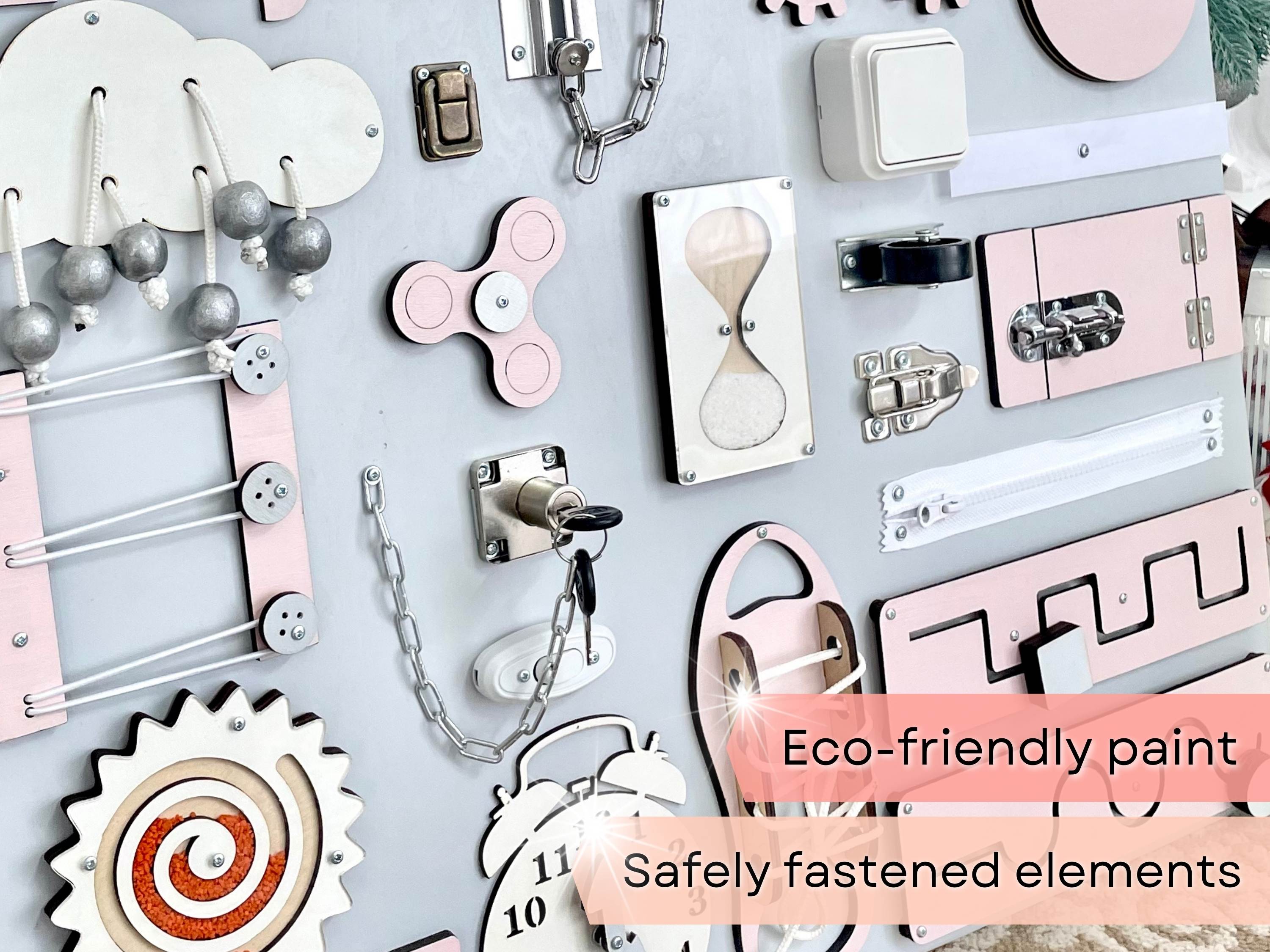 Pastel pink Busy Board MAXI featuring various interactive elements for children's development.