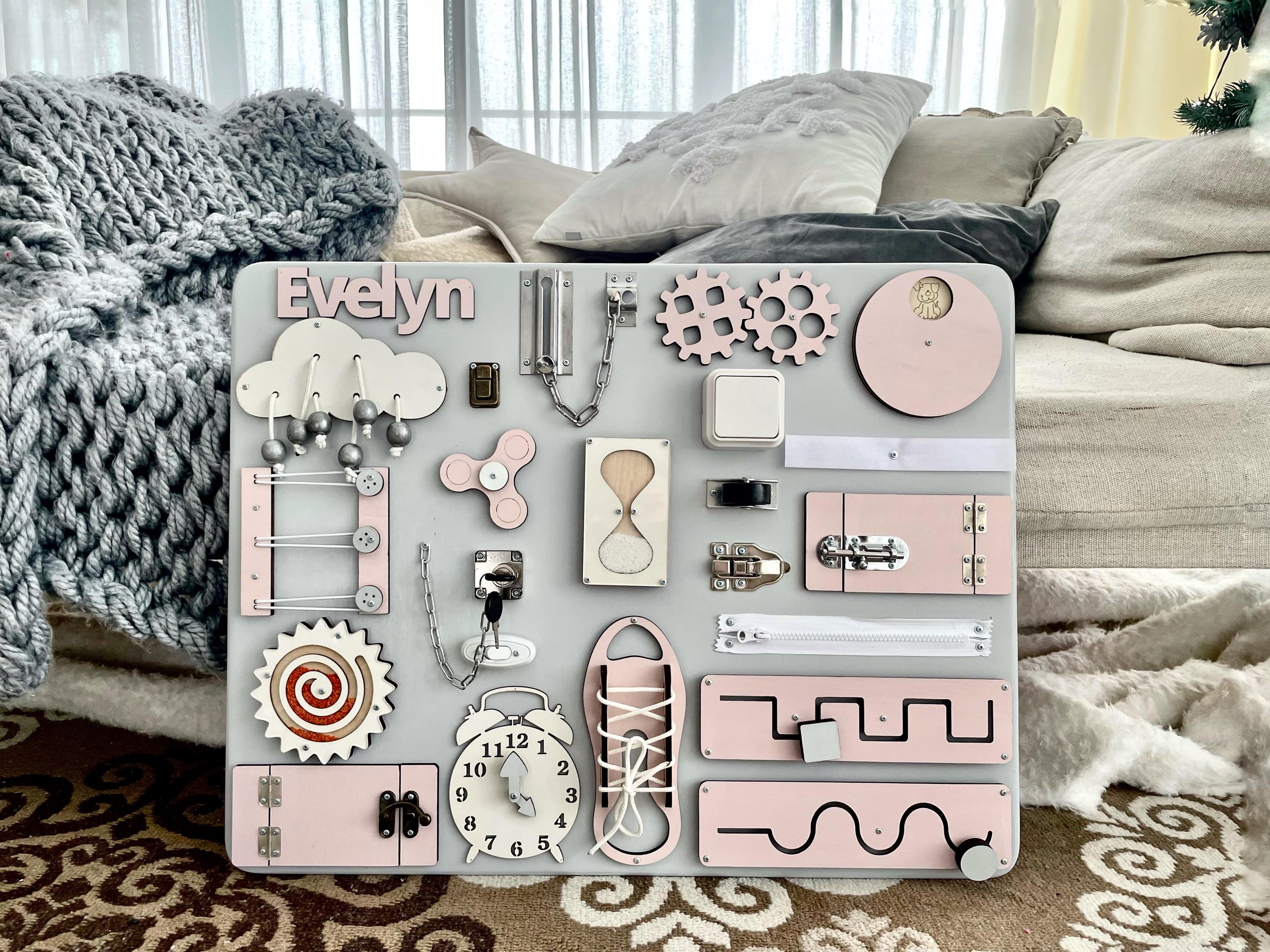 Pastel pink Busy Board MAXI featuring various interactive elements for children's development.