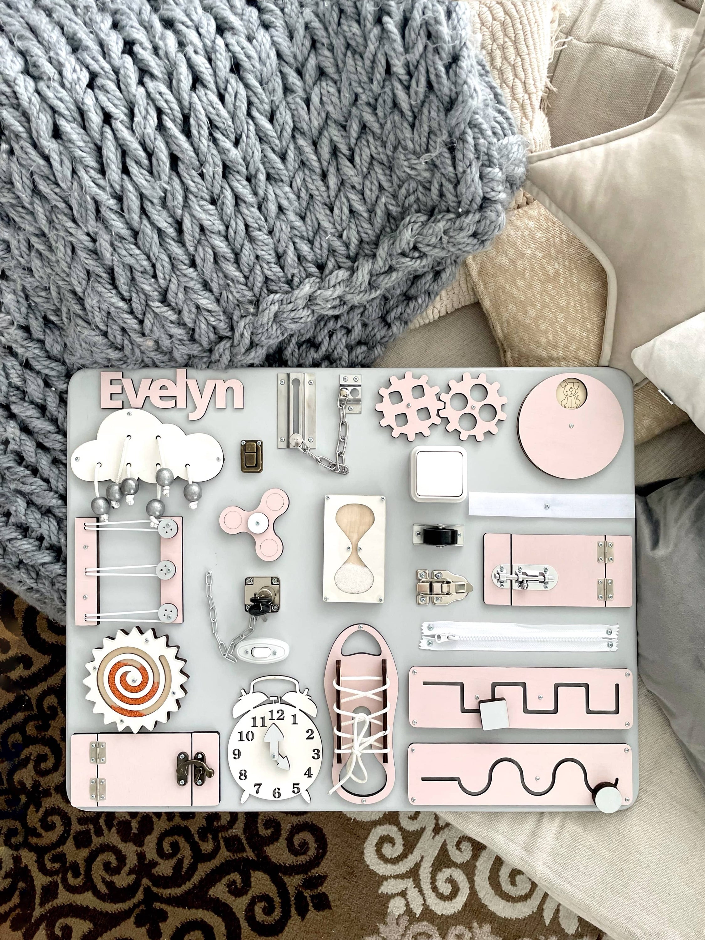 Pastel pink Busy Board MAXI featuring various interactive elements for children's development.